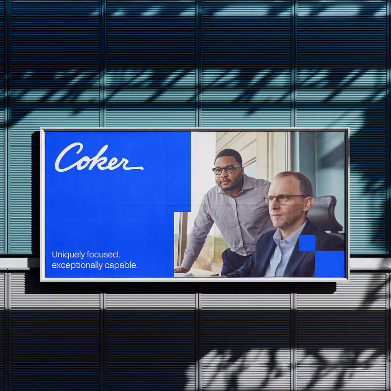 Billboard featuring two men in an office setting with the text 'Coker' and the tagline 'Uniquely focused, exceptionally capable.'
