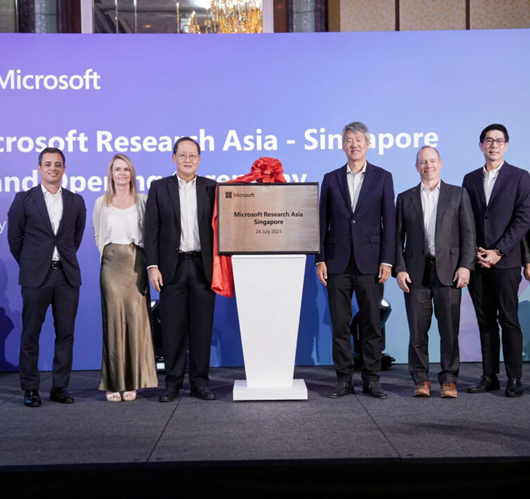 People standing in line on a stage next to a podium reading Microsoft Research Asia Singapore.